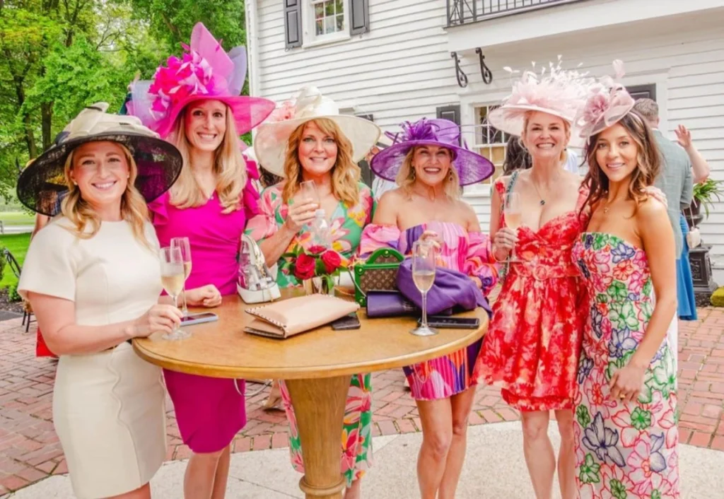 Women wearing colorful dresses and large hats