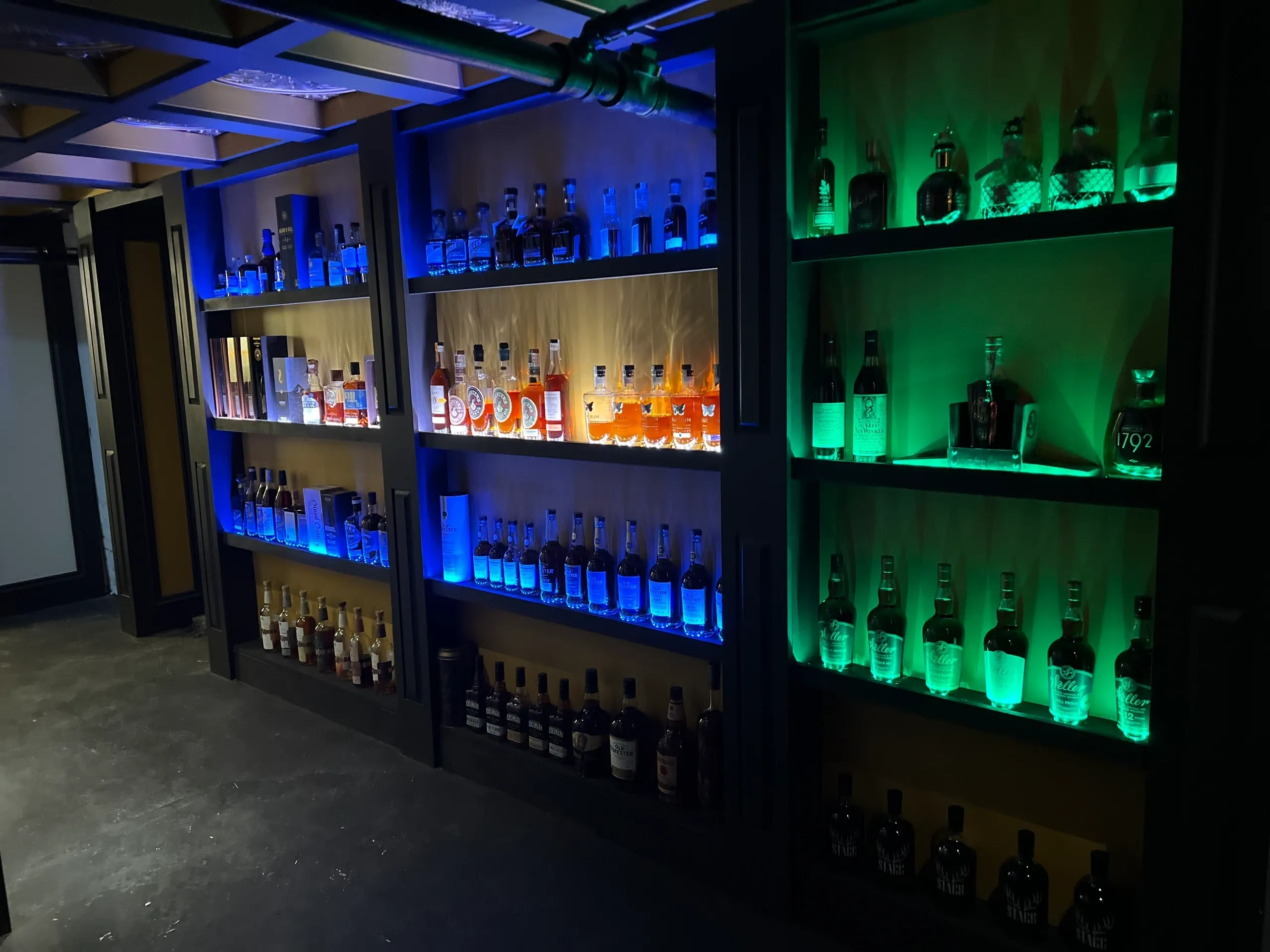 Blue and green backlit liquor bottles on shelves
