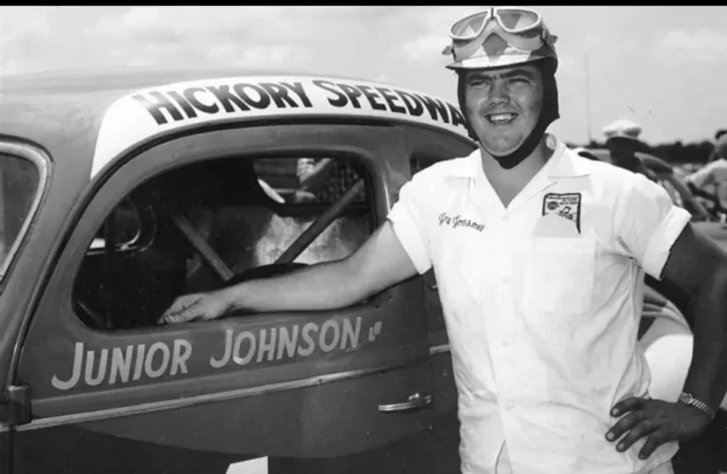Smiling driver standing beside vintage race car