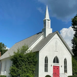 White wooden church with red doors and steeple